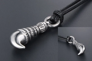 Macro detail of men's wolf tooth pendant with spiral textures and braided cord