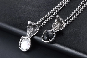 Detailed view of cobra pendants with black and white gemstones on retro steel chains