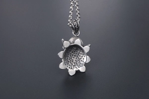 Macro shot of vintage silver sunflower pendant with intricate textures and bead chain