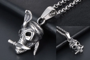 Macro shot of punk style skull pendant featuring a cobra and dagger on a steel chain
