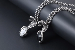 Close-up of silver cobra pendants with sparkling black and clear gemstone accents