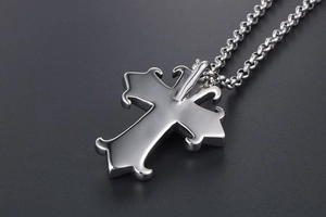 Close-up of gothic silver cross pendant with intricate scrollwork on a rolo chain link