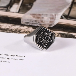 Retro stainless steel signet ring with star and eye relief design on a display card