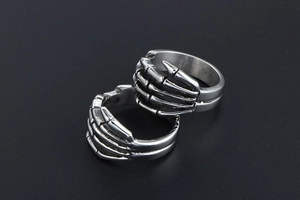 Macro detail of two punk gothic skull hand rings with intricate skeletal bone textures