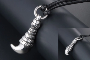 Detailed macro view of a silver titanium steel wolf tooth pendant with ornate carvings