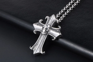 Macro detail of gothic cross pendant featuring a 3D skull with retro oxidized finish