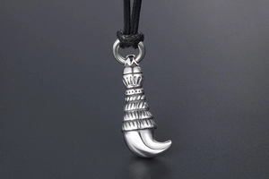 Macro shot of silver wolf tooth pendant with ornate textures and black cord