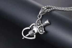 Vue macro d'un pendentif gothique crâne et épée avec détail de cœur en acier vintage