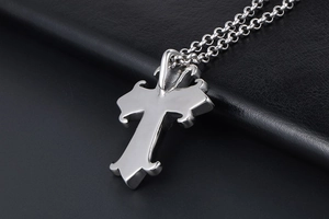 Close-up of gothic silver cross pendant with thick link chain on black leather background