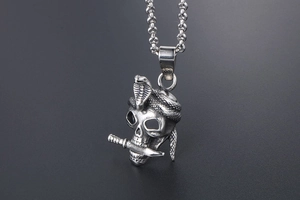 Detailed close-up of retro silver skull pendant with cobra and dagger in punk style
