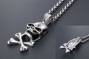 Macro shot of punk skull and crossbones pendant with rolo chain in silver finish