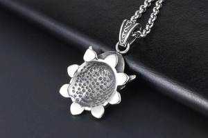 Macro view of matte silver sunflower pendant with honeycomb texture and round link chain