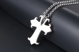Macro shot of silver gothic cross pendant with intricate curved edges on thick chain
