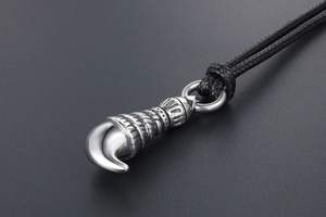Macro shot of polished silver wolf tooth pendant with retro engraved patterns and cord