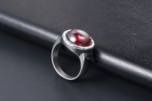 Gros plan d'une bague en acier titane avec une pierre grenat rouge ovale sur cuir noir