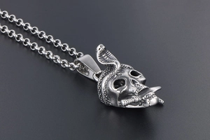 Detailed view of punk silver skull pendant with a cobra and dagger on a rolo chain