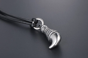 Macro detail of men's wolf tooth pendant with tribal engravings and black leather cord