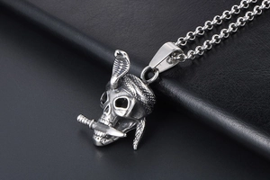 Close-up of gothic stainless steel skull pendant with cobra and dagger on dark leather