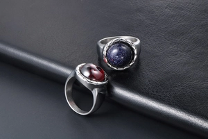 Détail de bagues rétro en acier titane avec grès bleu et grenat rouge sur cuir noir