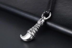 Detail of a vintage wolf tooth pendant with ornate carvings on black leather background