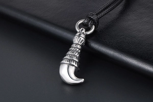 Macro shot of polished stainless steel wolf tooth pendant with intricate carvings