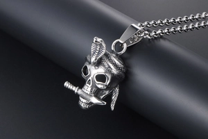 Macro detail of gothic skull pendant with cobra and sword in polished titanium steel