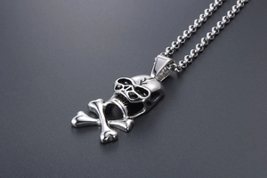 Close-up of a silver skull and crossbones pendant necklace with a thick steel chain