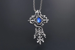 Detailed view of vintage gothic cross pendant with blue stone and dragon engravings