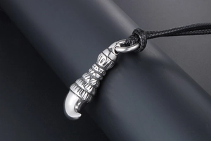 Close-up of vintage wolf tooth pendant with intricate tribal carvings and polished steel tip