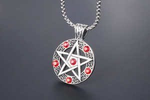 Macro detail of pentagram pendant with red crystals and celtic knot engraving