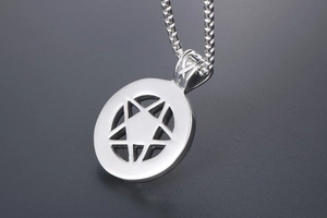 Detail of a polished silver pentagram pendant with box chain on a grey textured background