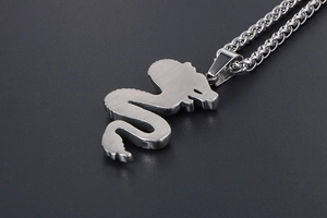 Macro side view of brushed stainless steel cobra pendant with braided chain detail