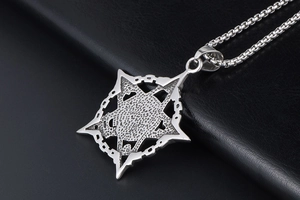 Macro shot of vintage hexagram pendant with hammer texture and box chain on black leather