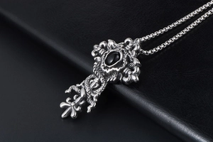 Macro shot of gothic cross pendant with snake texture and black gemstone on dark leather