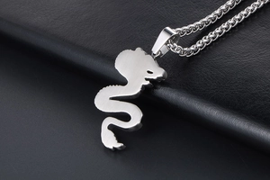 Close-up of a silver dragon pendant with brushed titanium steel texture on a leather background