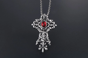 Macro shot of gothic cross pendant with red gemstone and double dragon carvings
