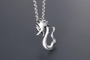 Macro shot of silver dragon pendant necklace with wheat chain on textured dark background