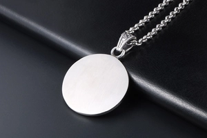 Macro shot of silver-tone round pendant with brushed texture on vintage rolo chain necklace