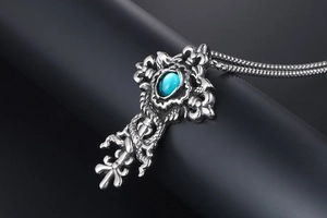 Macro shot of silver gothic cross pendant with blue stone and detailed snake wrap