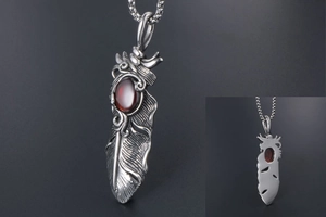 Macro detail of vintage titanium steel feather pendant with inlaid red gemstone