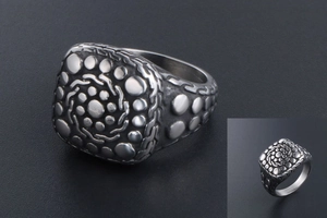 Macro shot of vintage titanium steel signet ring with pebble texture and geometric carvings
