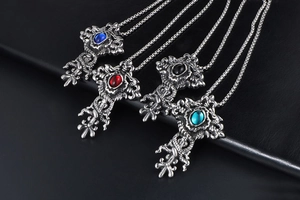 Close-up of four colored retro dragon cross necklaces on a black leather background