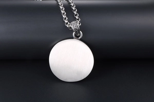 Close-up of brushed metal skull pendant with retro engraved bail and thick link chain