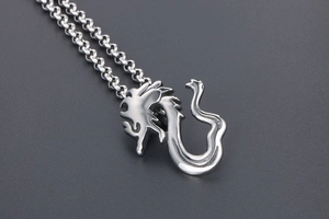 Detailed close-up of a silver dragon pendant on a heavy stainless steel rolo chain