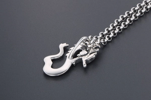 Macro close-up of a silver dragon pendant with vintage black engraving and bold link chain