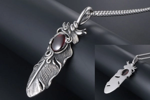 Macro shot of titanium steel feather pendant with red ruby inlay and vintage texture