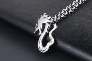 Close-up of polished silver dragon pendant on a black leather texture display