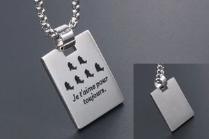 Detail of titanium steel tag necklace with dolphins engraving and romantic French text