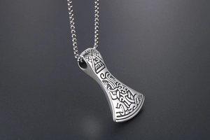 Close-up of a silver stainless steel Viking axe pendant with intricate rune engravings