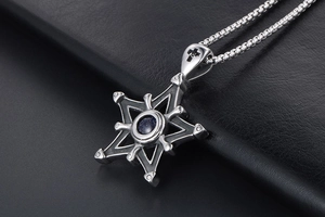 Macro d'un pendentif étoile rétro en acier avec pierre bleue et gravure de croix
